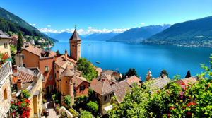 A panoramic view of Lake Geneva featuring serene blue waters and the majestic Alps in the background. In the foreground, a charming medieval village with warm stone buildings and narrow cobblestone streets, adorned with vibrant flower boxes. This peaceful scene evokes a mood of